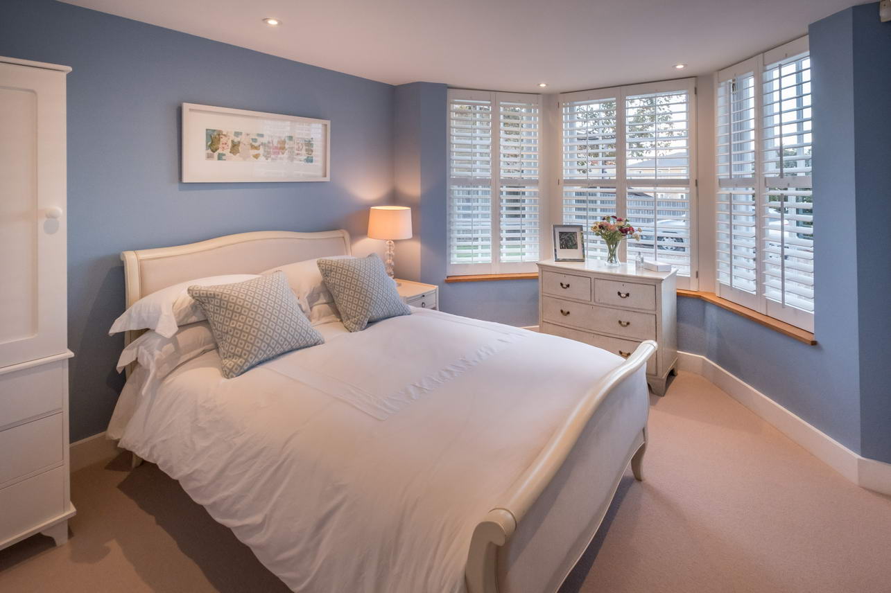 Luxurious bedroom in a holiday home - double bed with white bedding, blue walls and cream carpet.
