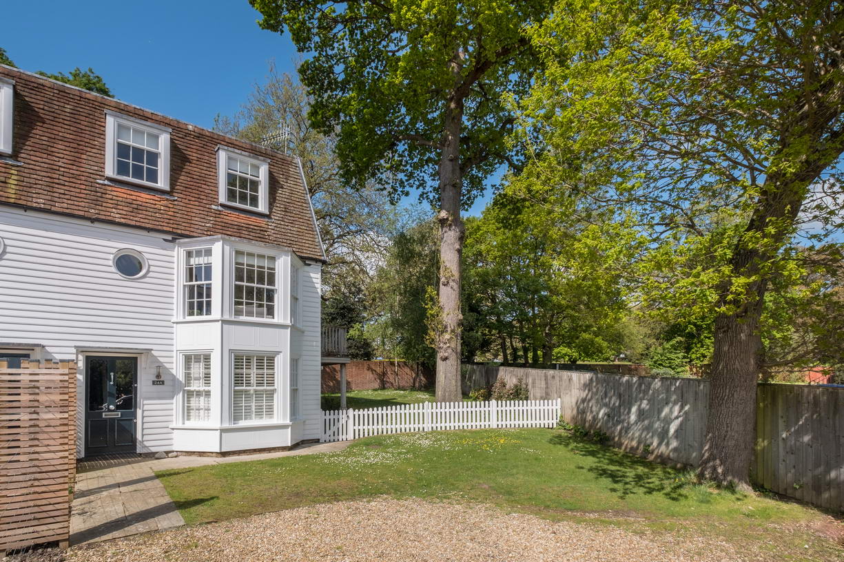 Front view of an attractive holiday home in Cowes with white panelling, white picket fence and garden.